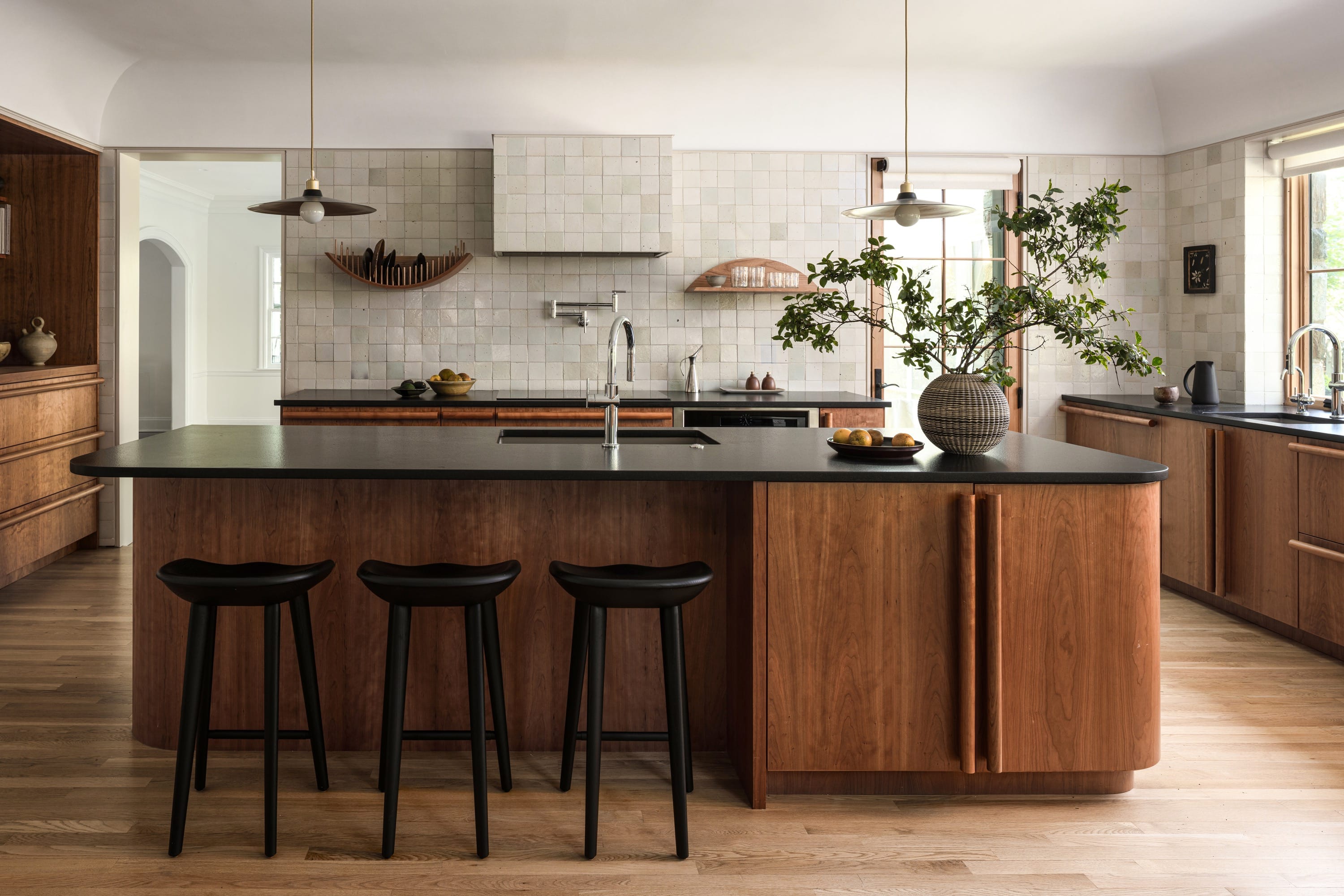Modern kitchen with bar stools and marble backsplash.