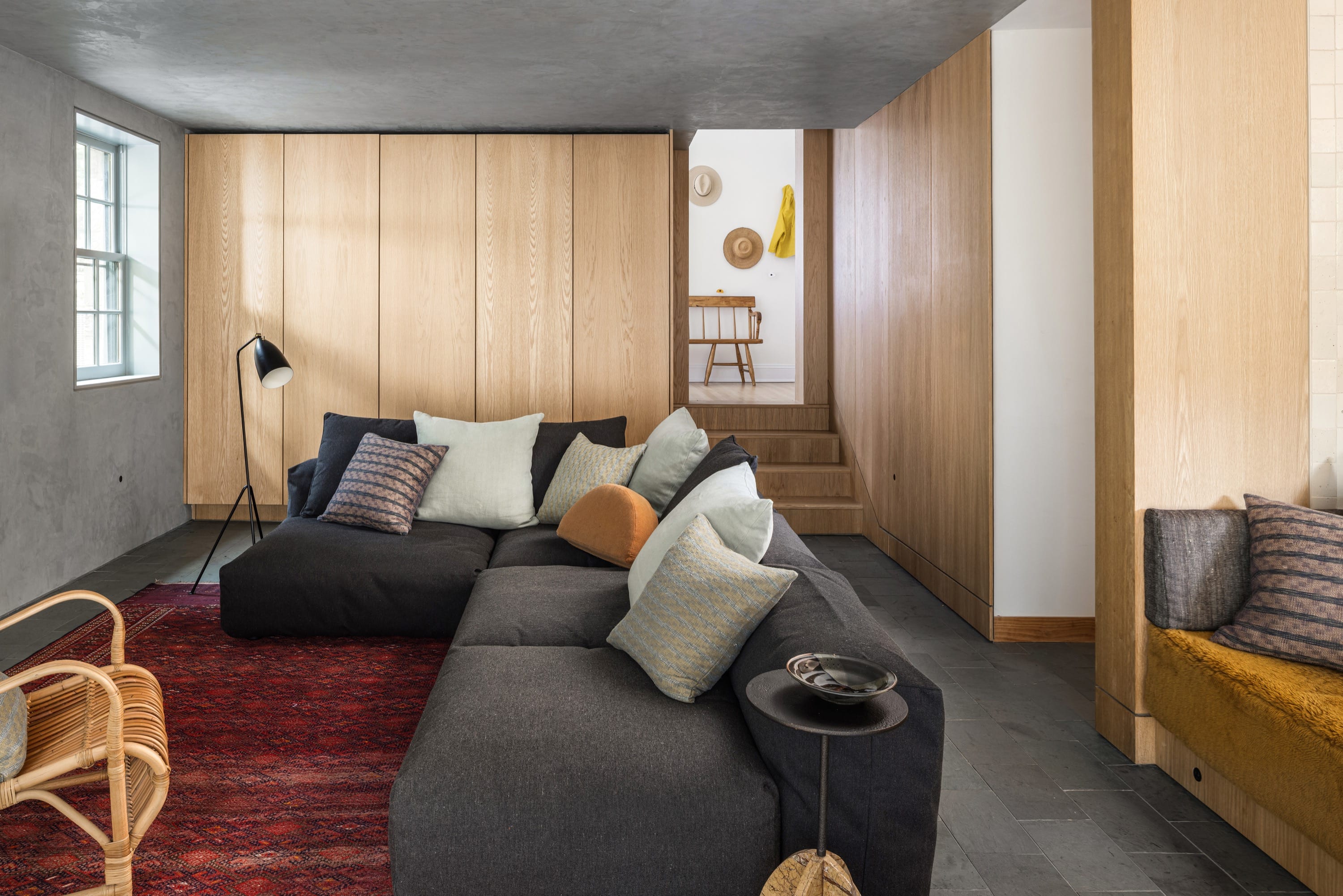Family room with sectional sofa, rug, and wood paneling.