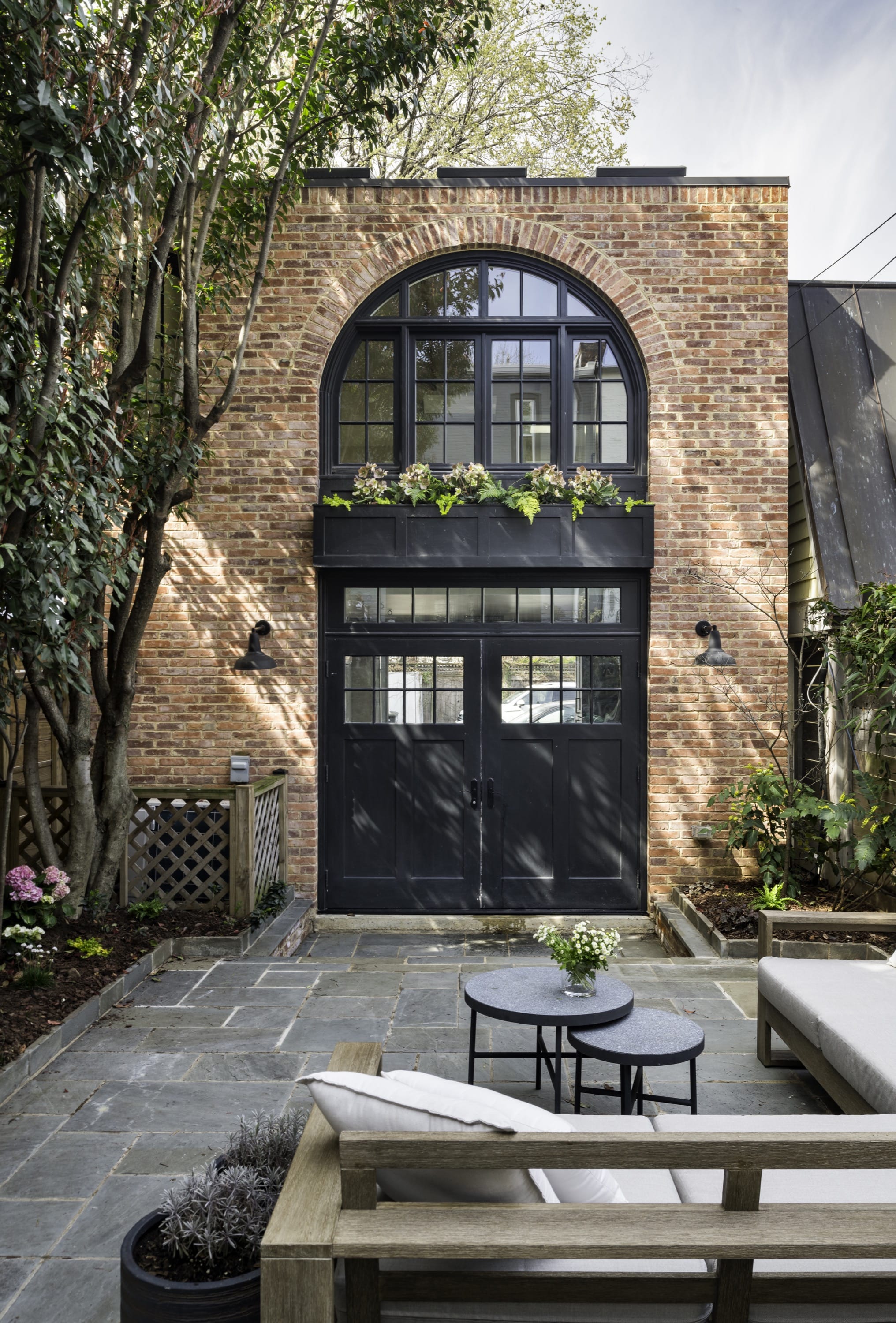 Brick townhouse with arched black door and patio seating.