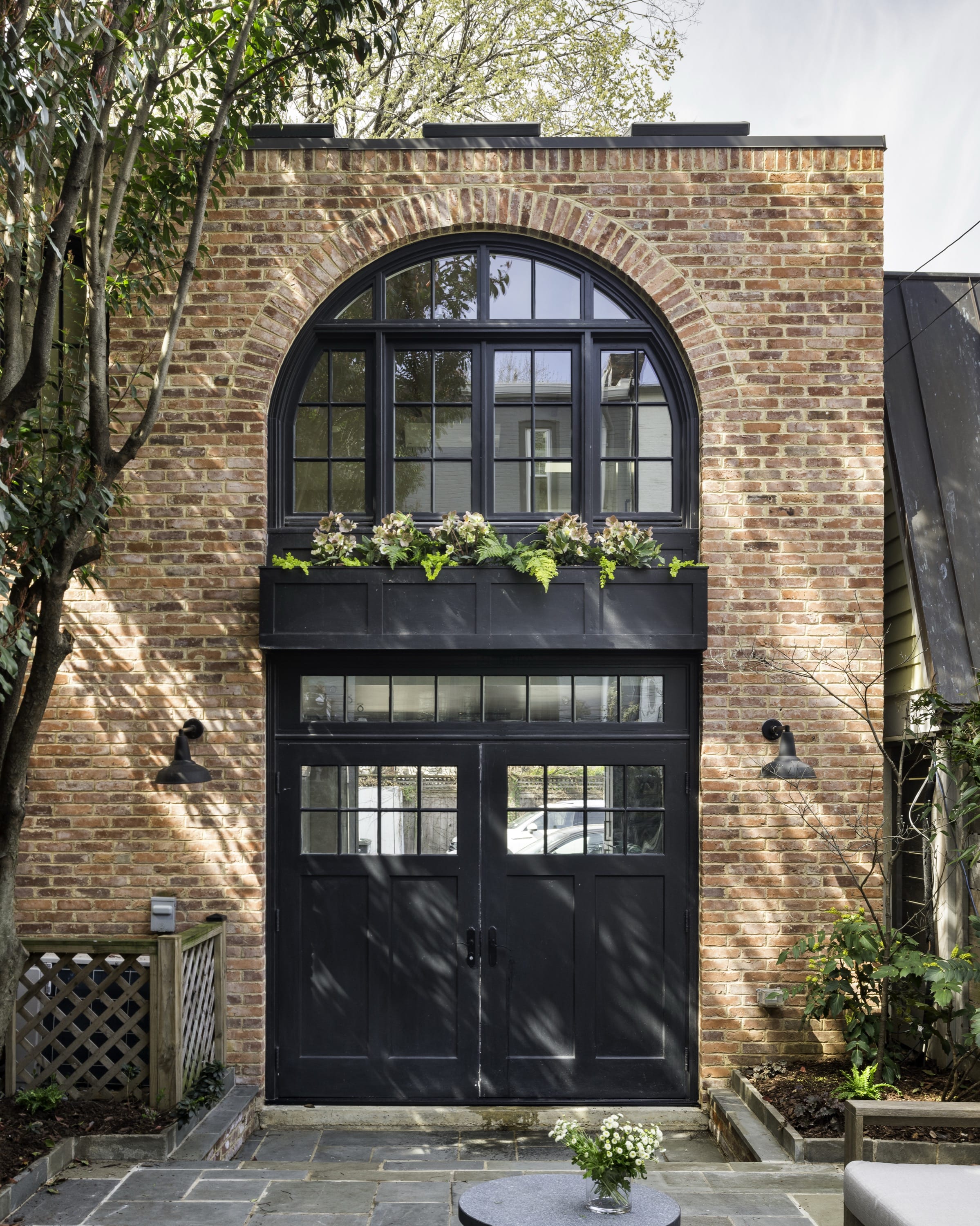 Front view of brick townhouse with arched windows and planters.
