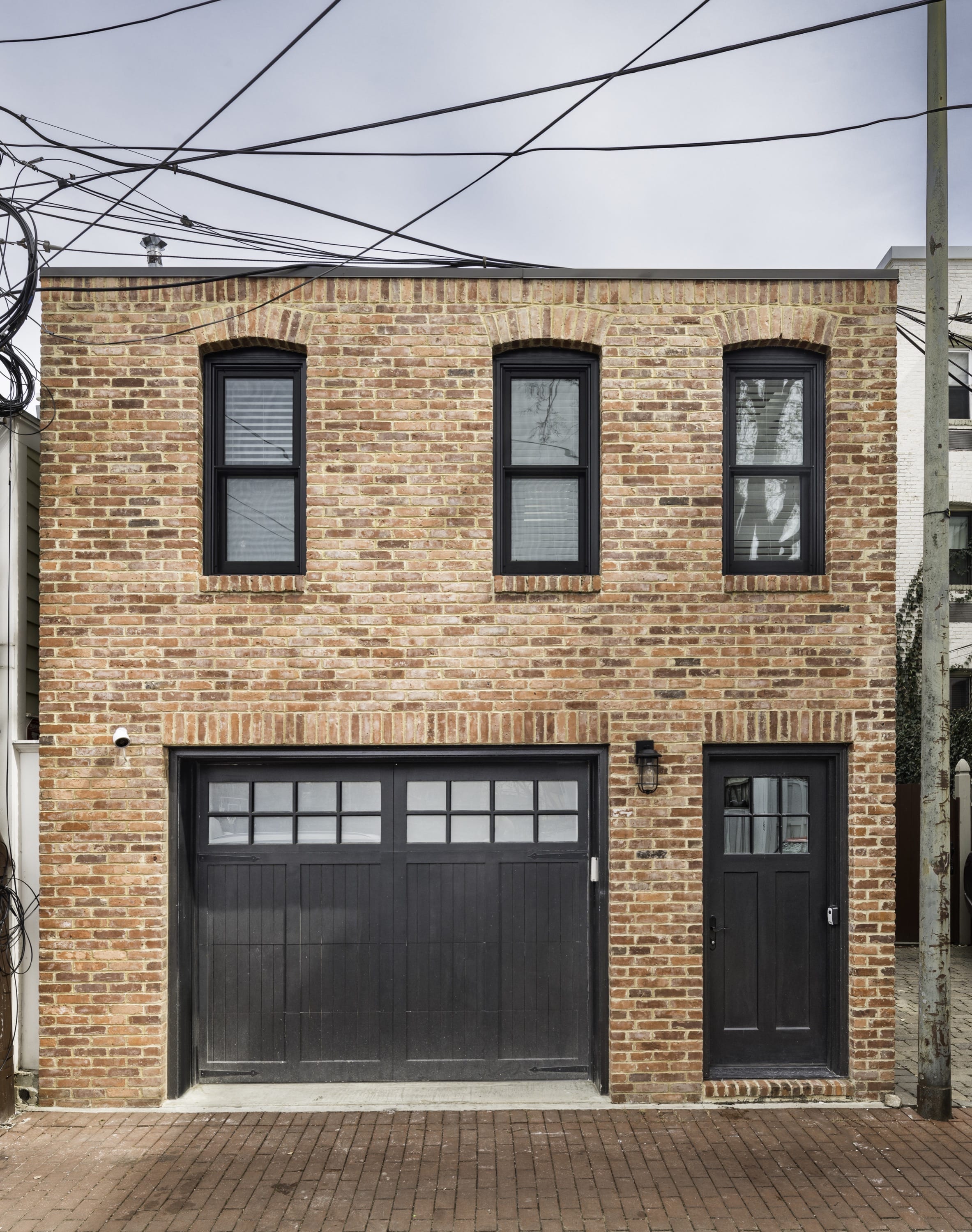 Two-story brick townhouse with garage and black door.