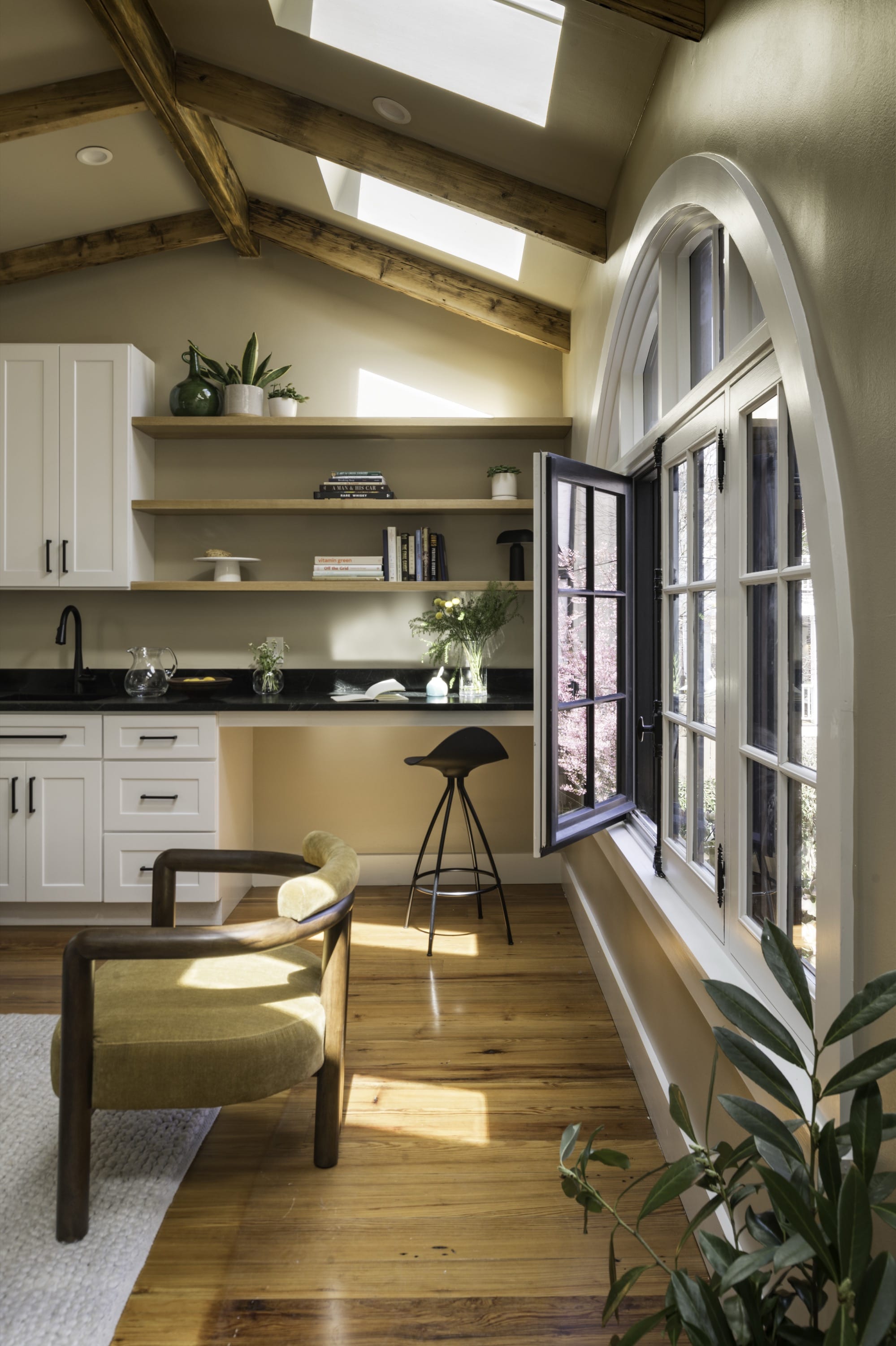 Living room with beams, arched window, and open kitchen.