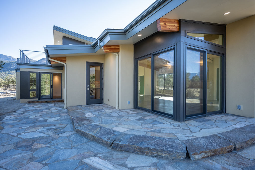 modern house exterior with large windows, angled rooflines, and a flagstone patio