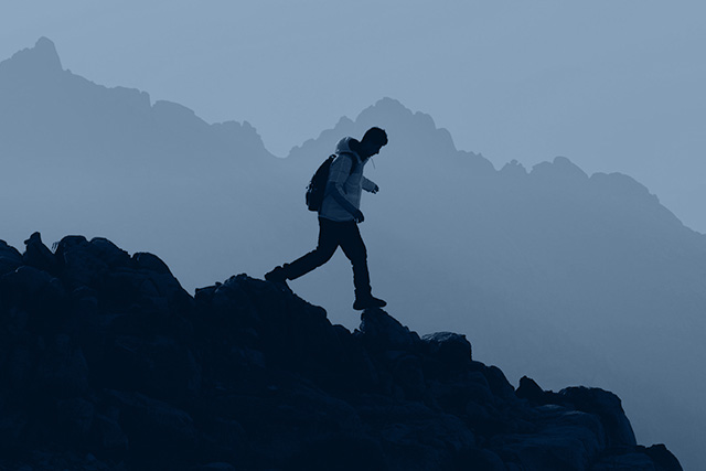 Hiker climbing a trail, symbolizing adaptability and perseverance.