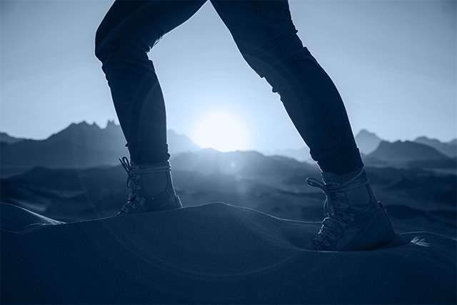 Person trekking through desert, symbolizing the celebration of movement forward.