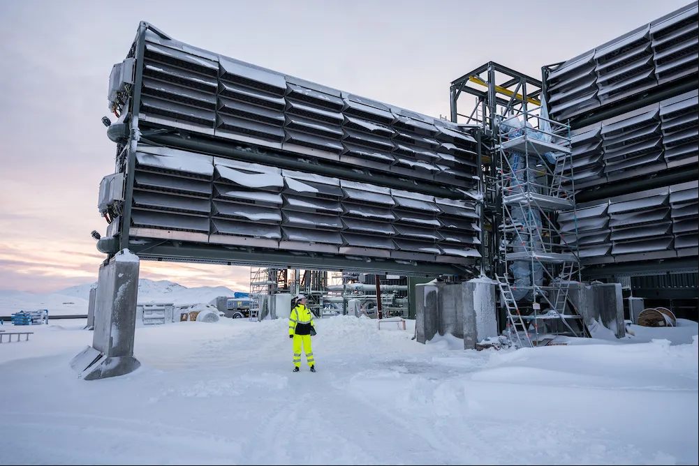 A worker in front of an air capture facility in the snow