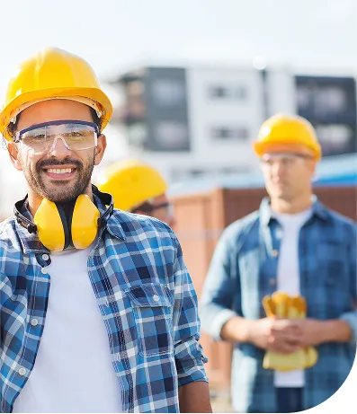 A man wearing a yellow safety helmet and yellow protective earmuffs, dressed in a blue shirt.