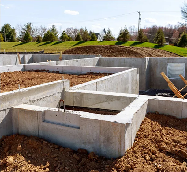 Concrete house foundation with soil backfill on a construction site during early building phase.