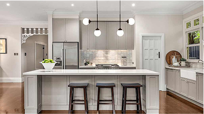 Modern kitchen with white cabinetry, a large island with seating, and round pendant lights hanging over the island