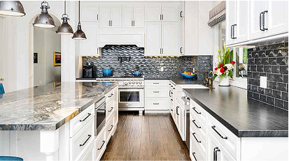 Modern kitchen featuring white cabinets and countertops, with a dark textured tile backsplash adding contrast and style.