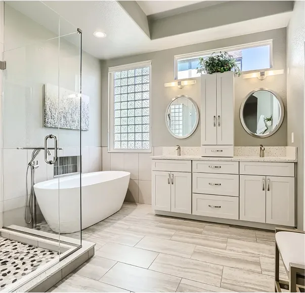 Spacious modern bathroom with a freestanding bathtub, glass shower enclosure, white vanity cabinets, and large frosted windows bringing in natural light