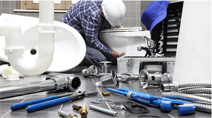 Plumber repairing a sink drain with tools and pipes spread out under the bathroom vanity