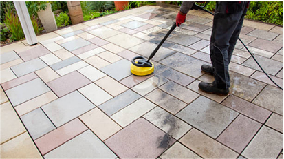Worker using a floor buffer to clean a newly installed paver patio, ensuring a spotless, finished outdoor surface.