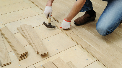 Worker installing wooden planks for a new hardwood floor.