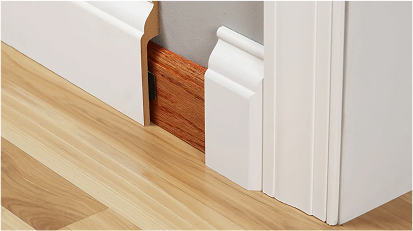 Baseboard and trim being installed at the floor and wall junction.