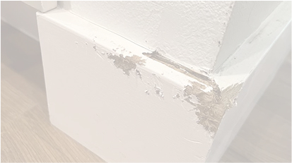 A close-up of damaged white trim or molding with peeling paint.