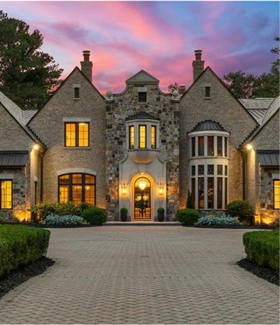 Luxury stone mansion with warm lights at sunset