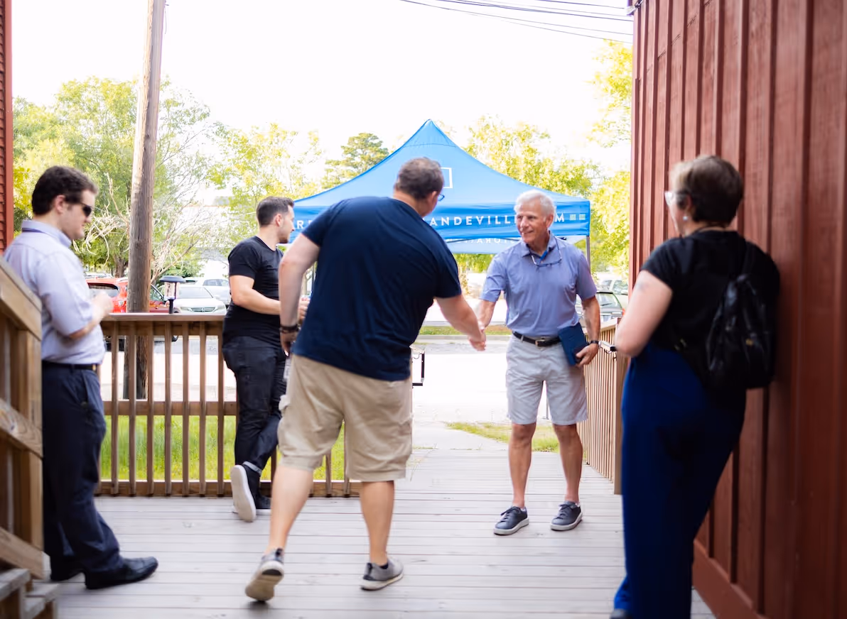 A member of the Northshore Gospel Network (Restoration Community Church) shaking hands and standing outside of the theatre they meet in