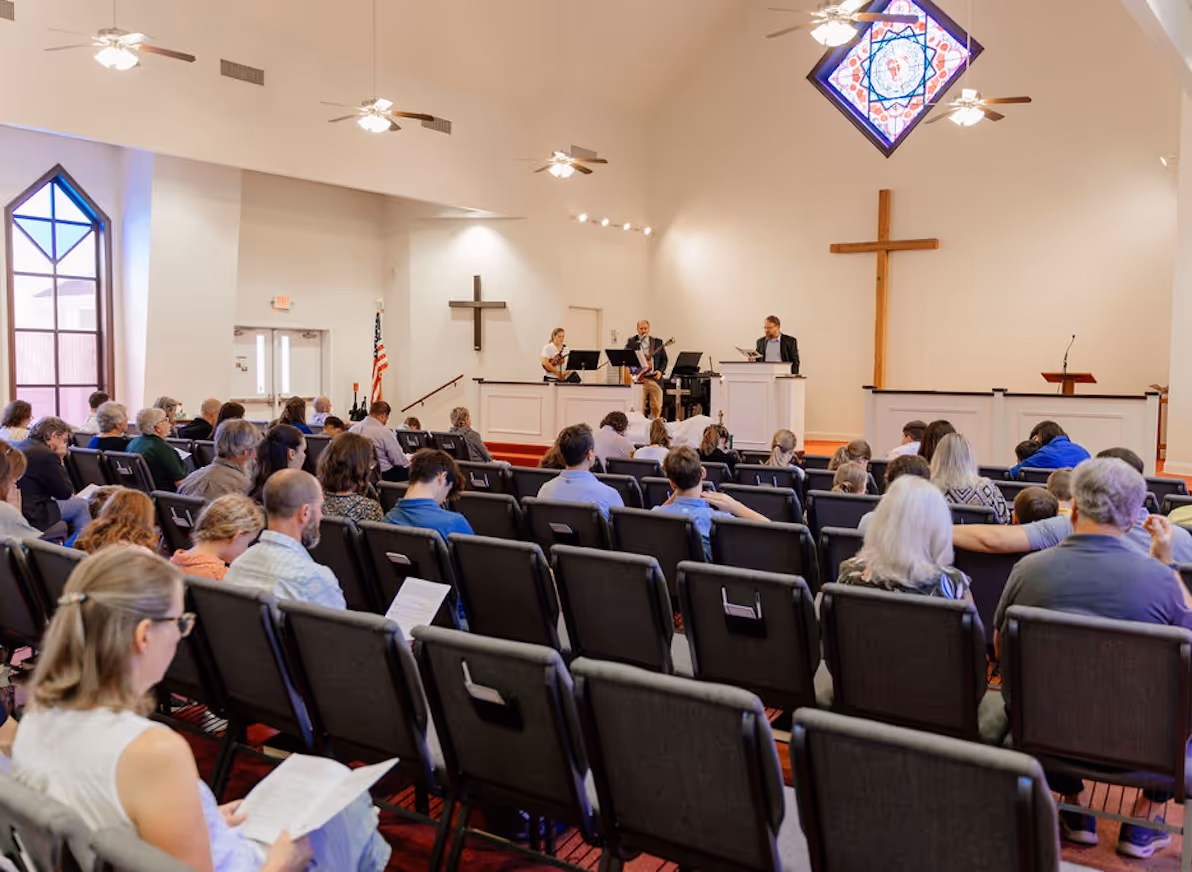 A member of the Northshore Gospel Network (Jason Wood) preaching in front of the congregation inside Faith Presbyterian Church