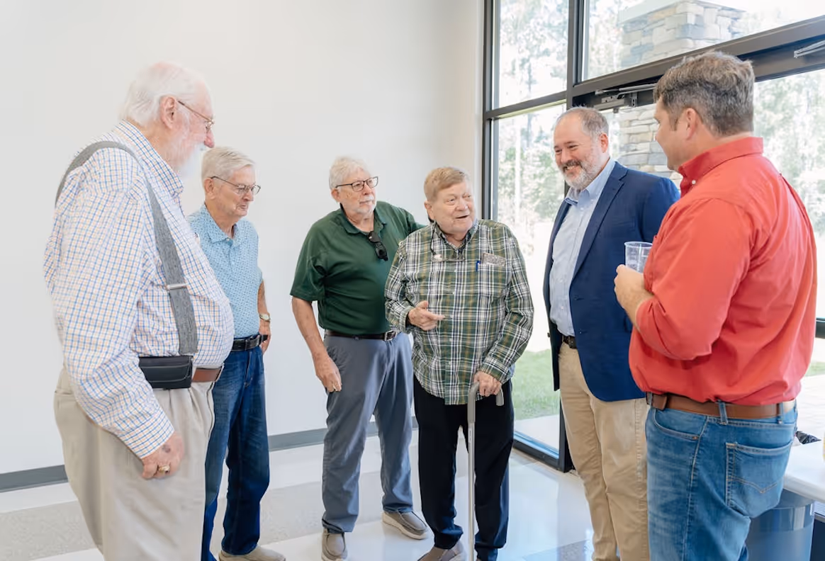 A group of men from Faith Presbyterian Church talking and smiling with one another at church