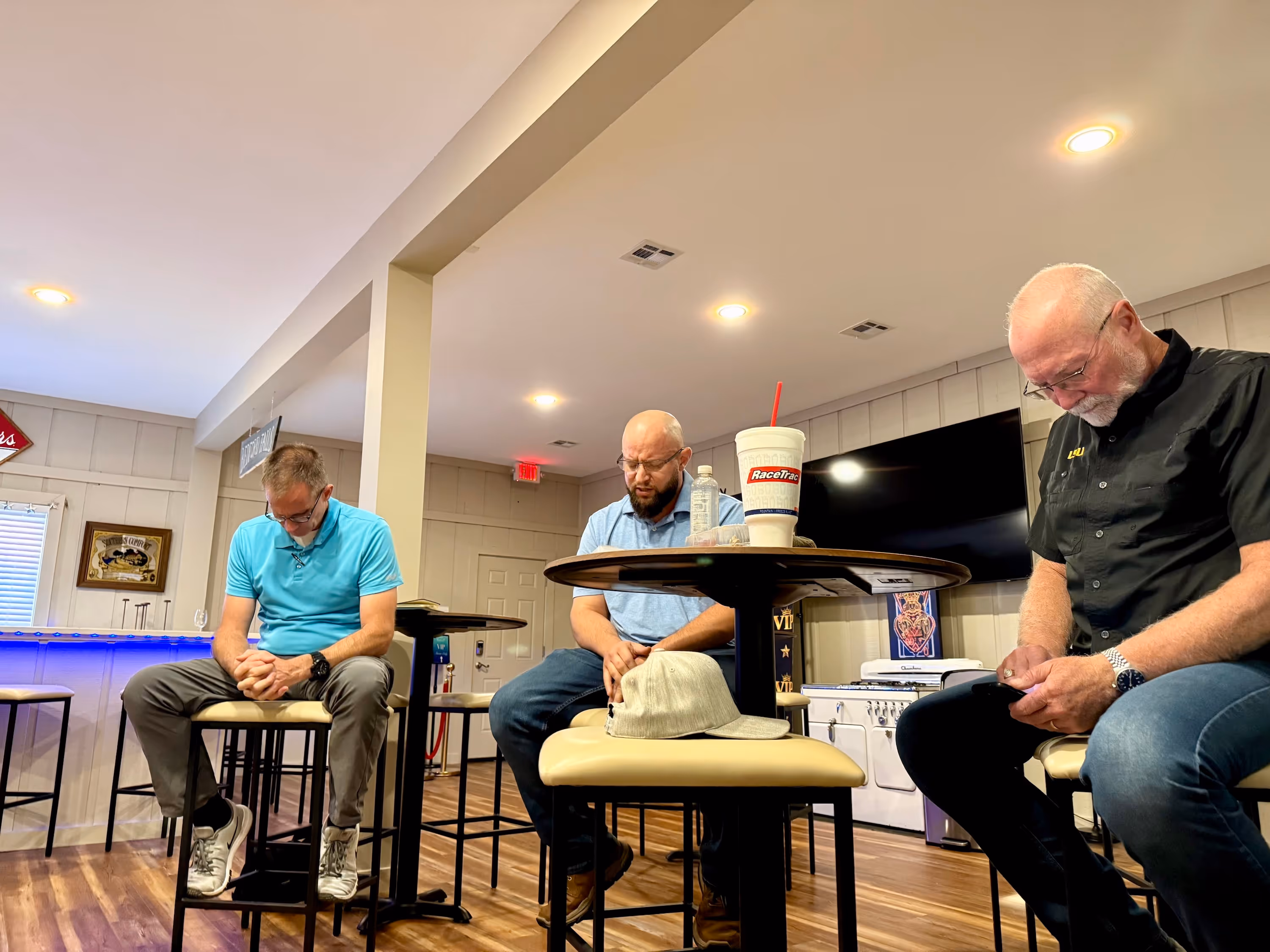 Three pastors bowing their heads in prayer at the Northshore Gospel Network's monthly Pastors' Prayer Lunch