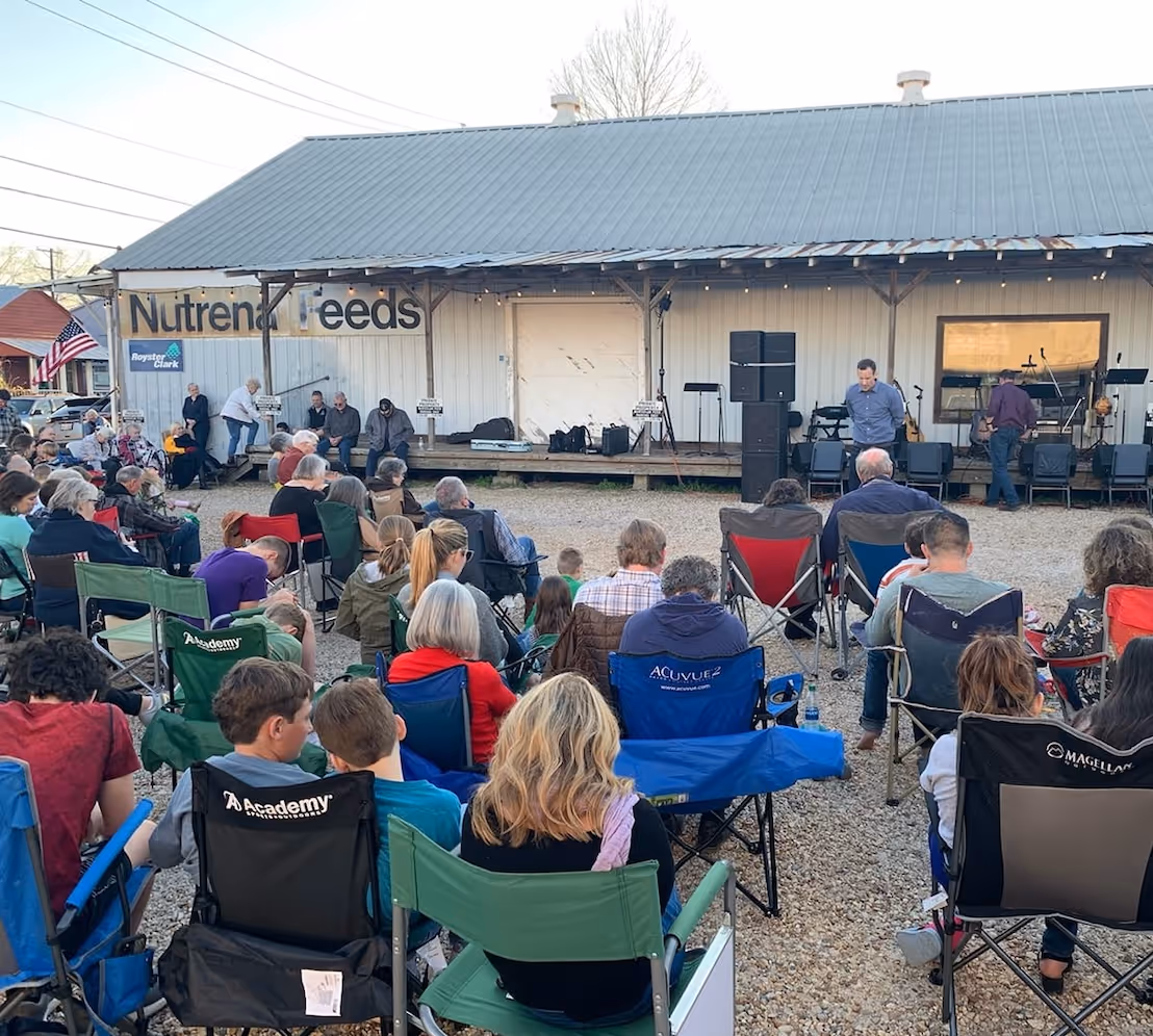 People sitting in chairs looking at people leading worship at an Awaken revival meeting outside