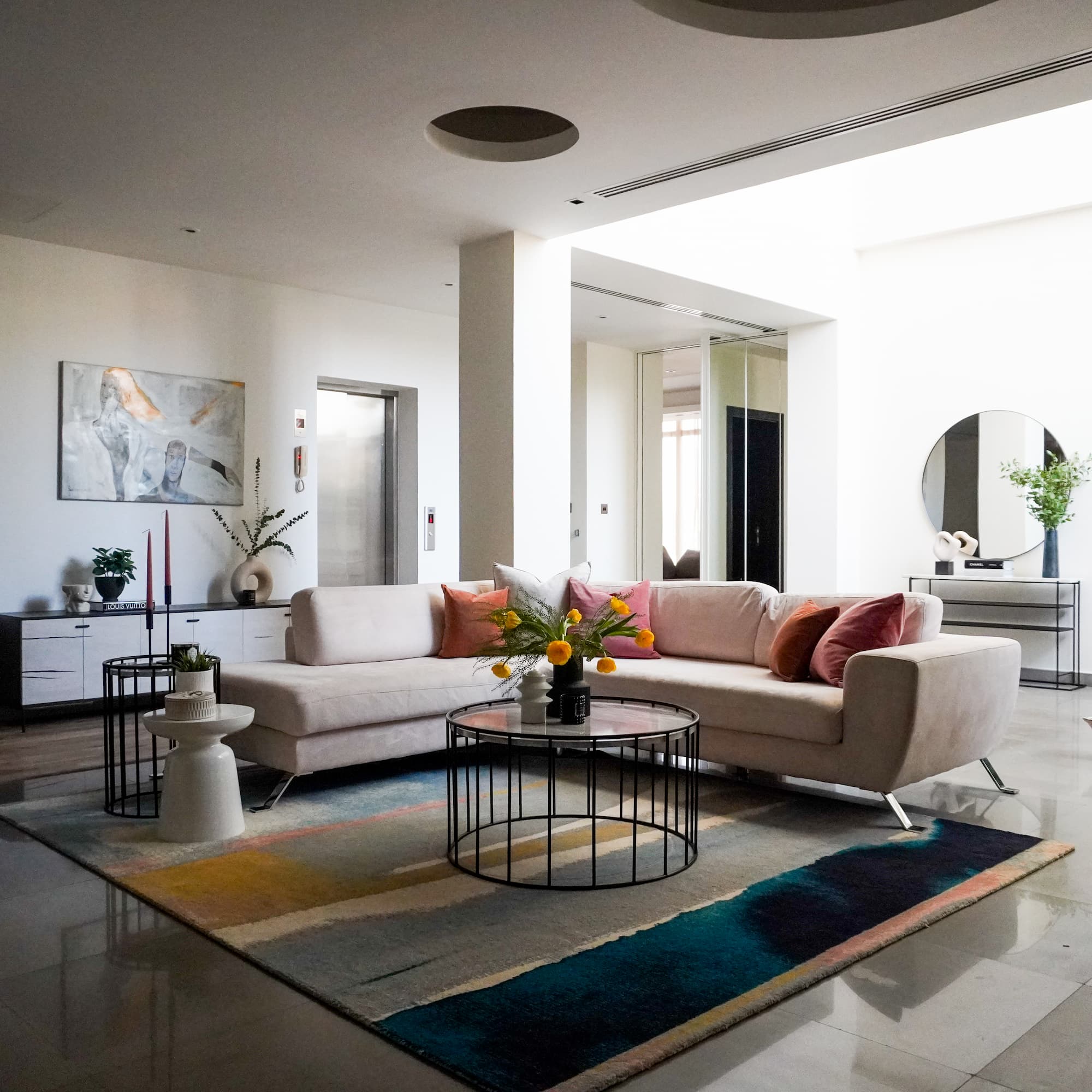 Modern open-plan living room with L-shaped cream sofa, colourful abstract rug, and contemporary art – available in our premium interior design package