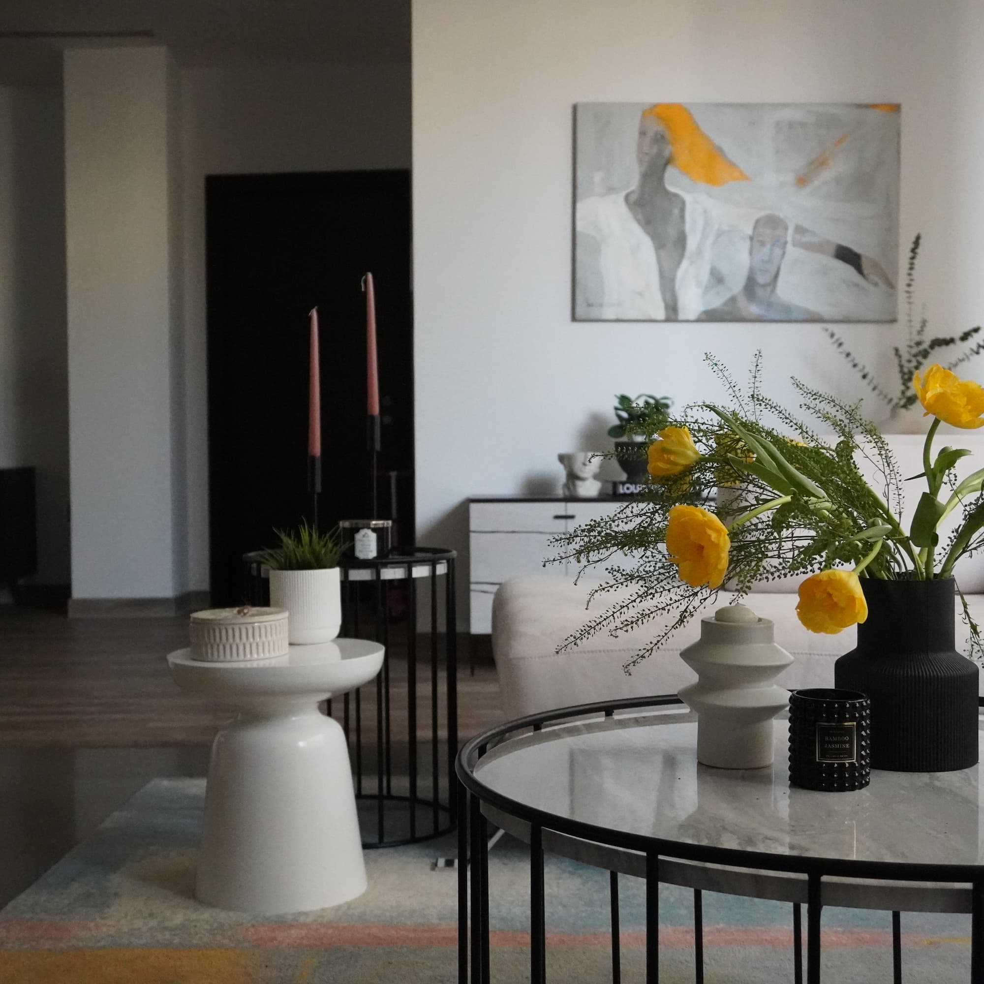 Detail shot of yellow floral arrangement on black wire-frame table with white sculptural stool – showcasing accessory styling from our interior design services