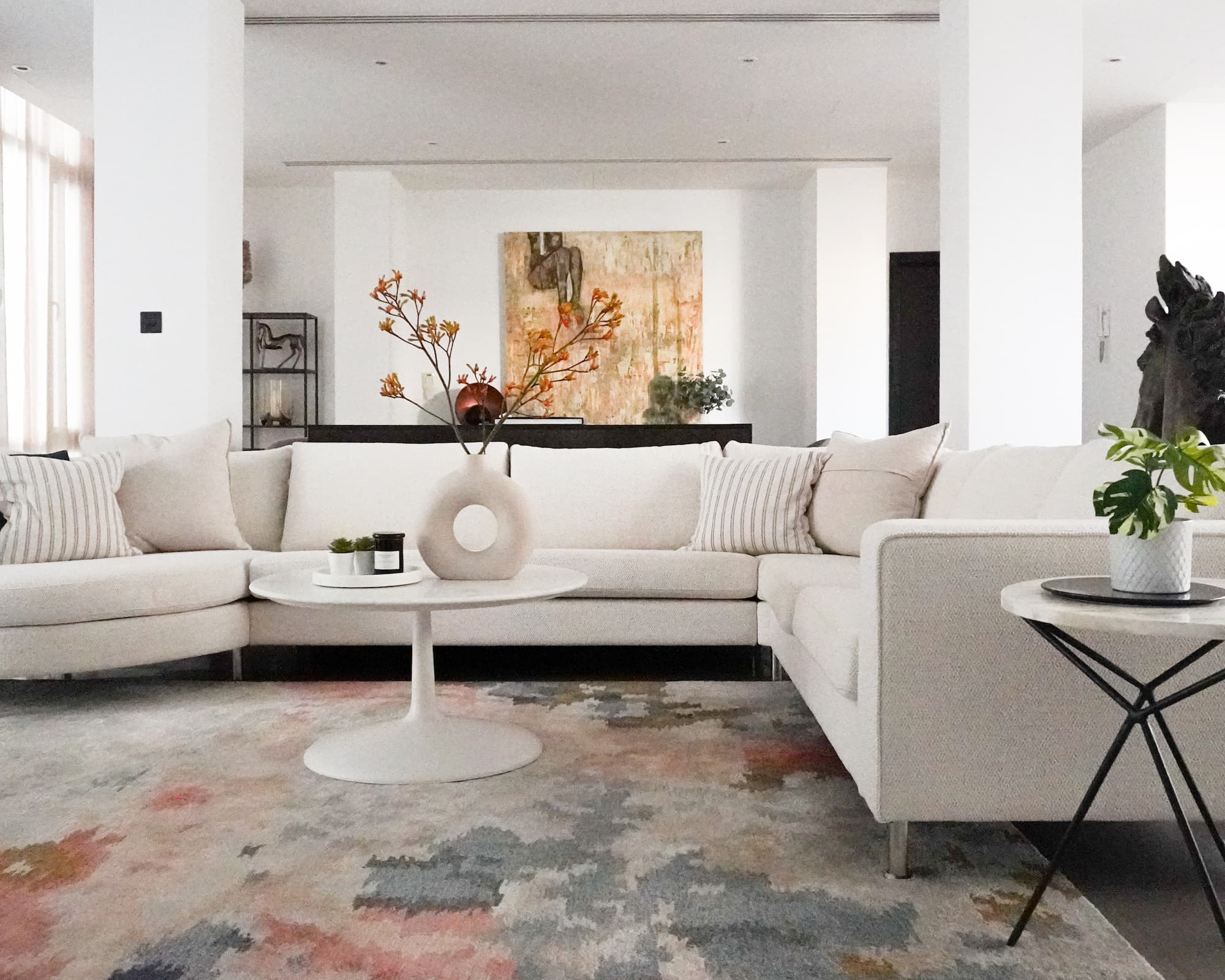 Elegant living room with two cream sofas, pastel rug, and bold portrait artwork – featured in our bespoke home interior design packages