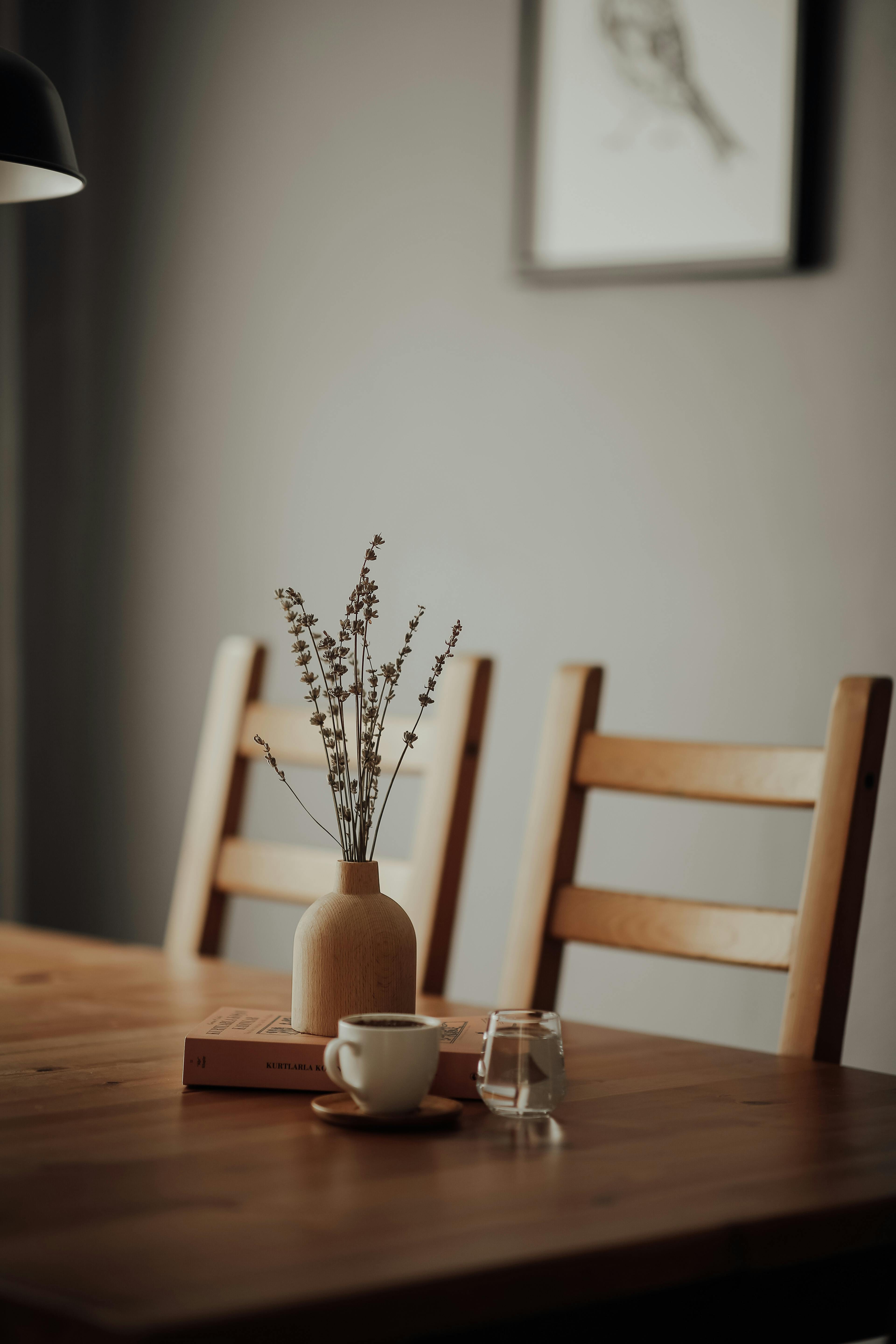 Simple rustic dining setup with natural wood furniture, dried lavender stems, and warm neutral tones.