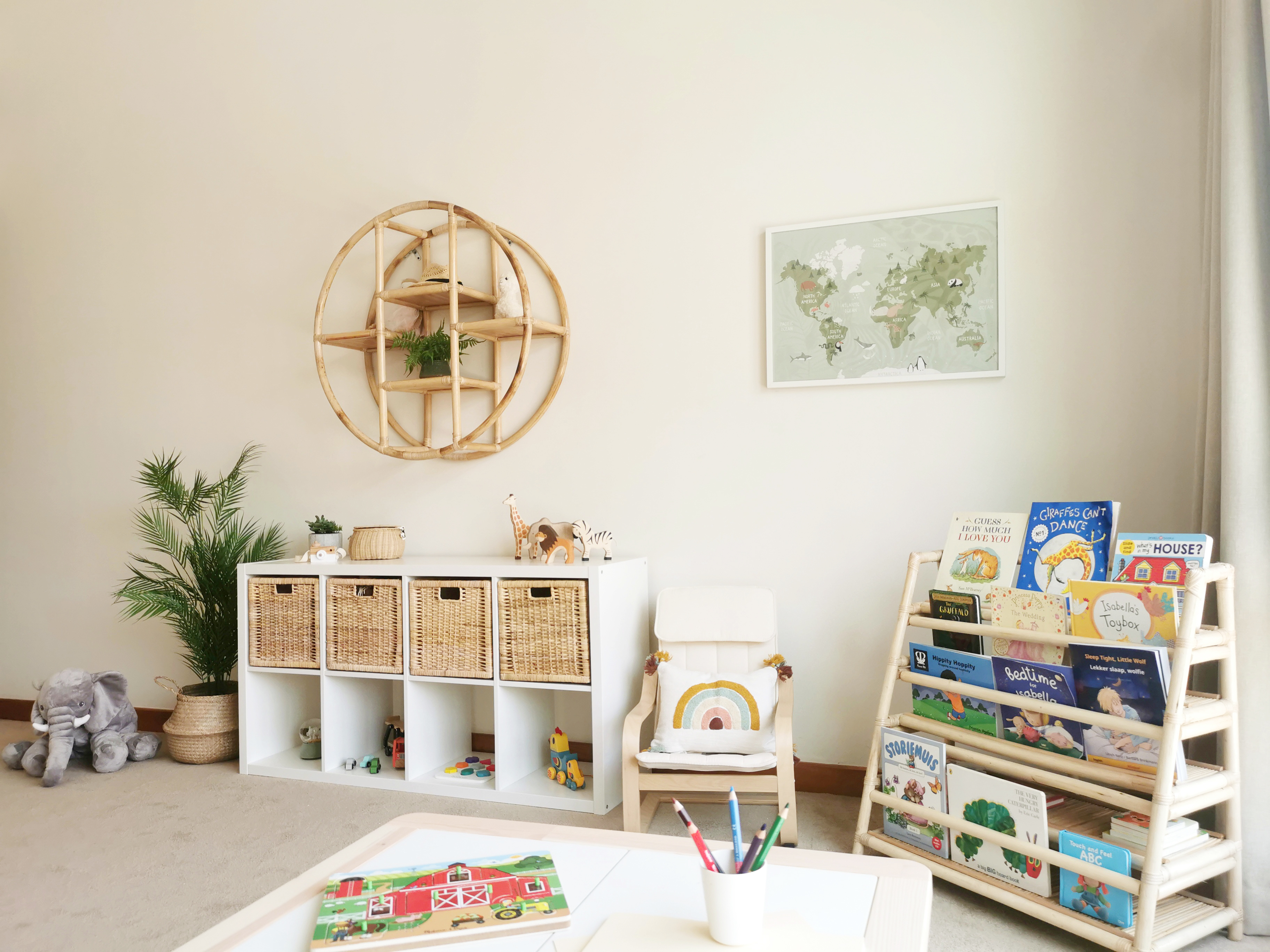 Bright and organised children’s playroom featuring wicker basket storage, open bookshelf, indoor plant, and playful rainbow décor elements.