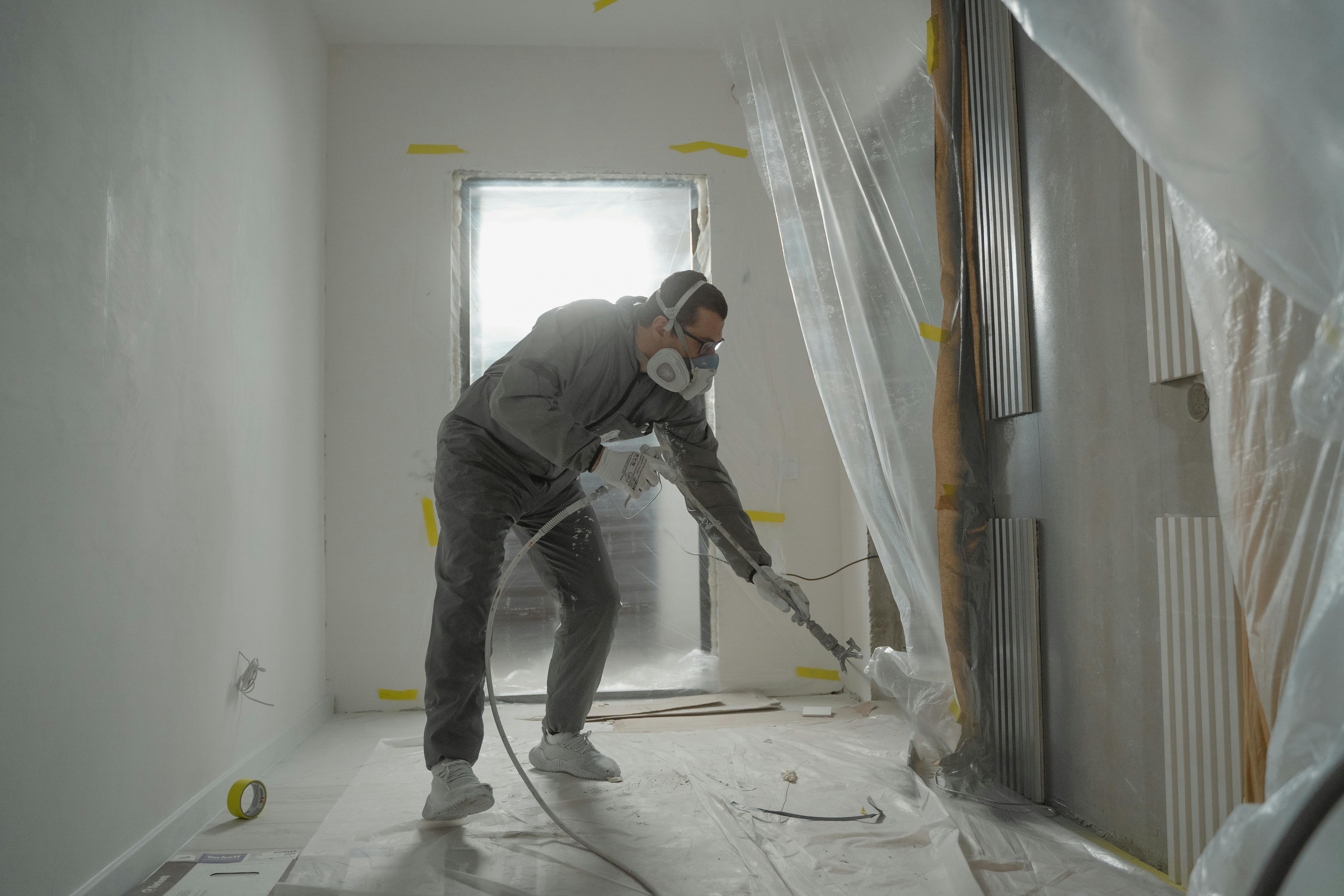 Tradesperson painting freshly plastered wall, part of our home renovation package finish work.