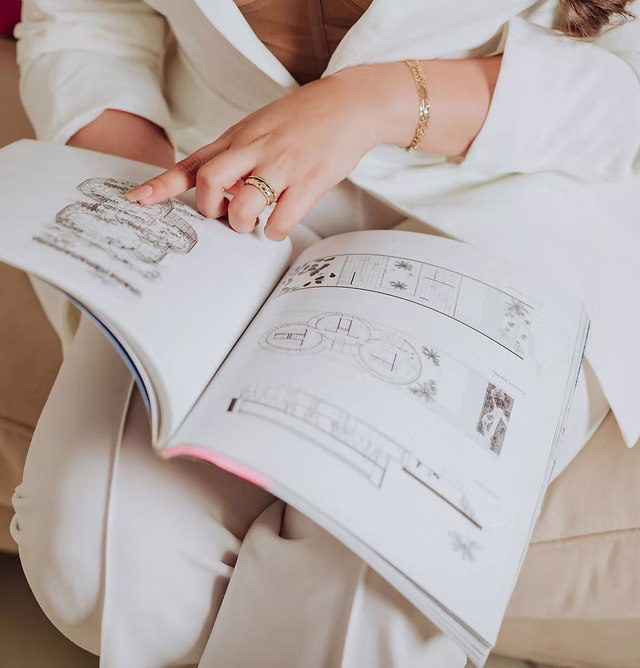 Interior designer reviewing architectural plans in a portfolio book, highlighting bespoke design planning and consultation process.