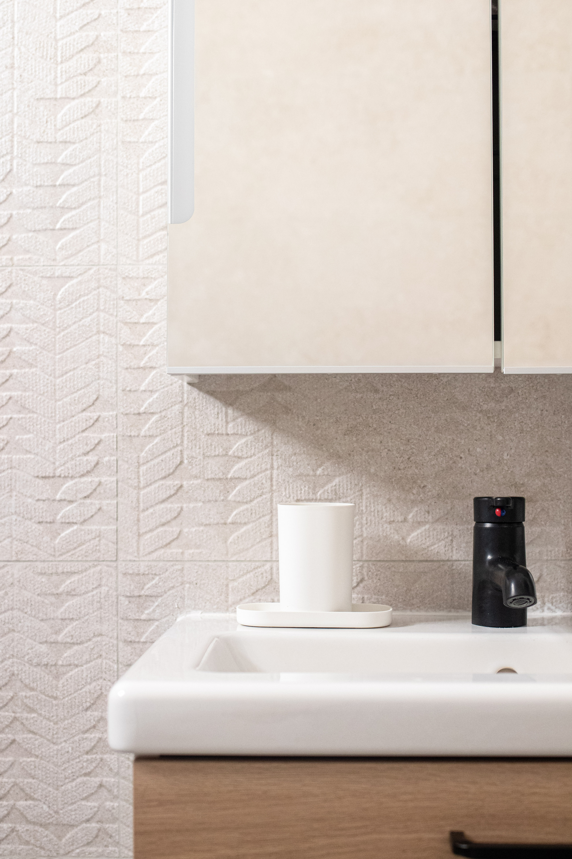Textured wall tiles, matt black mixer tap, and integrated storage. Modern bathroom finish suitable for future home refurbishments in Wakefield