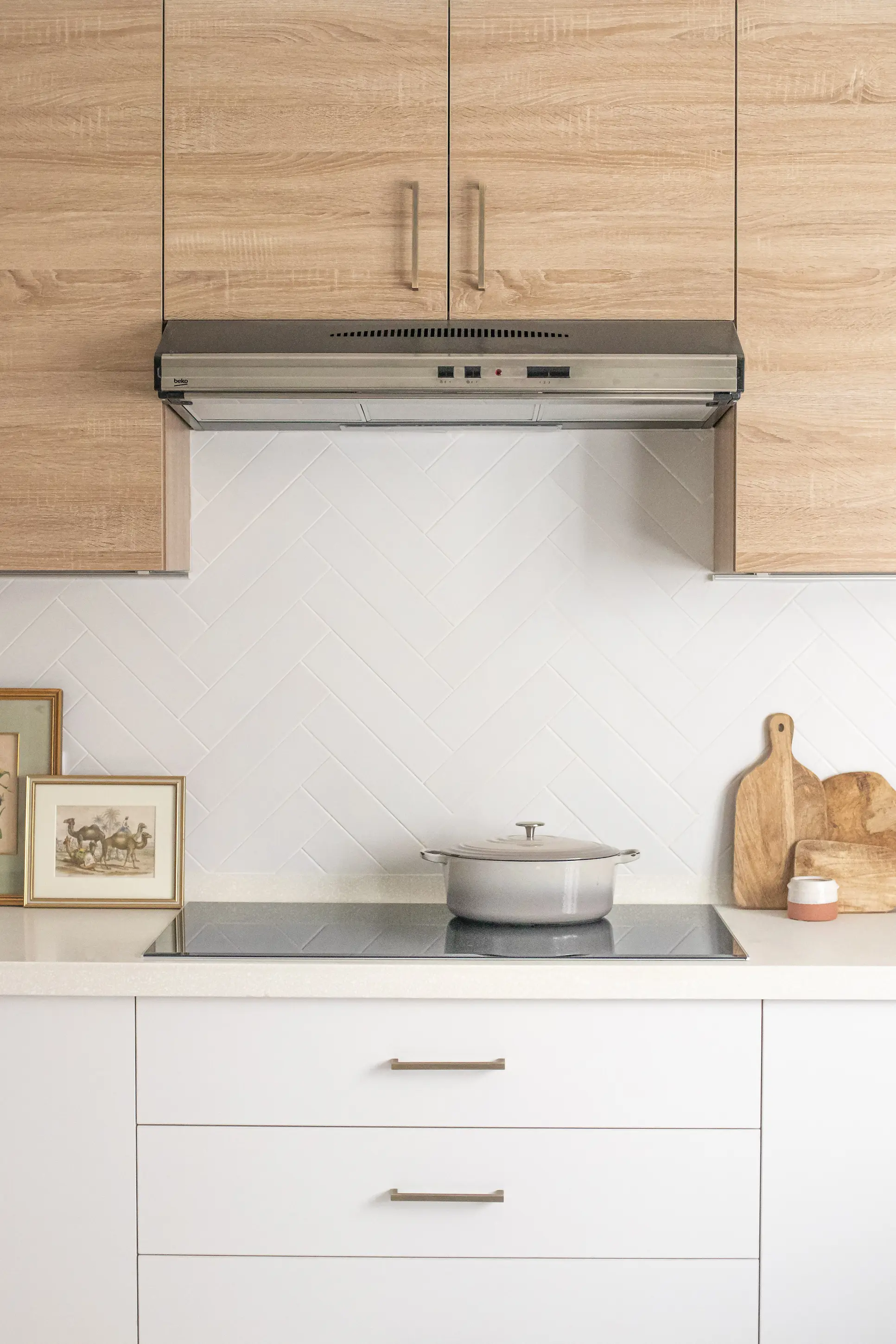 Modern kitchen with induction hob, integrated extractor fan, and oak upper cabinets above white cabinetry for a clean, functional design.