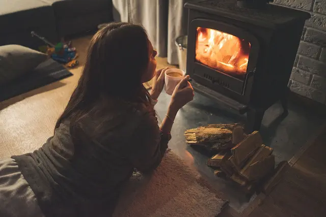 Cosy autumn evening at home with warm fire, wooden logs, and hot drink — Roberts Renovations showcasing autumn interior design trends 2025