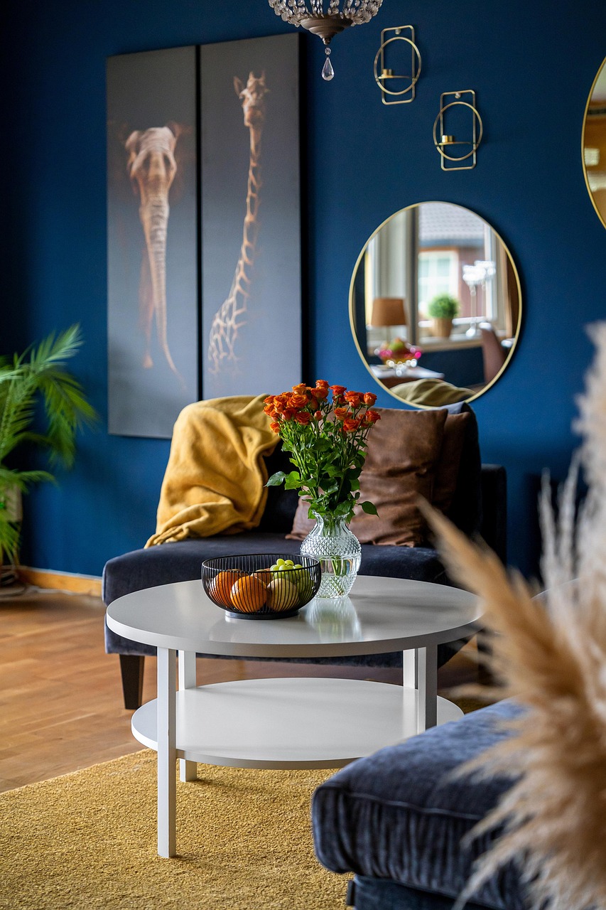 Small living room with deep blue walls, cosy armchair and round coffee table, featuring warm lighting and bold colour design – Roberts Renovations modern living room inspiration Yorkshire
