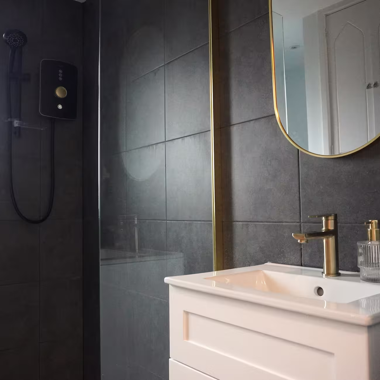 Modern bathroom with black wall tiles, walk-in shower, and bronze fittings designed for a refined and space-efficient layout.