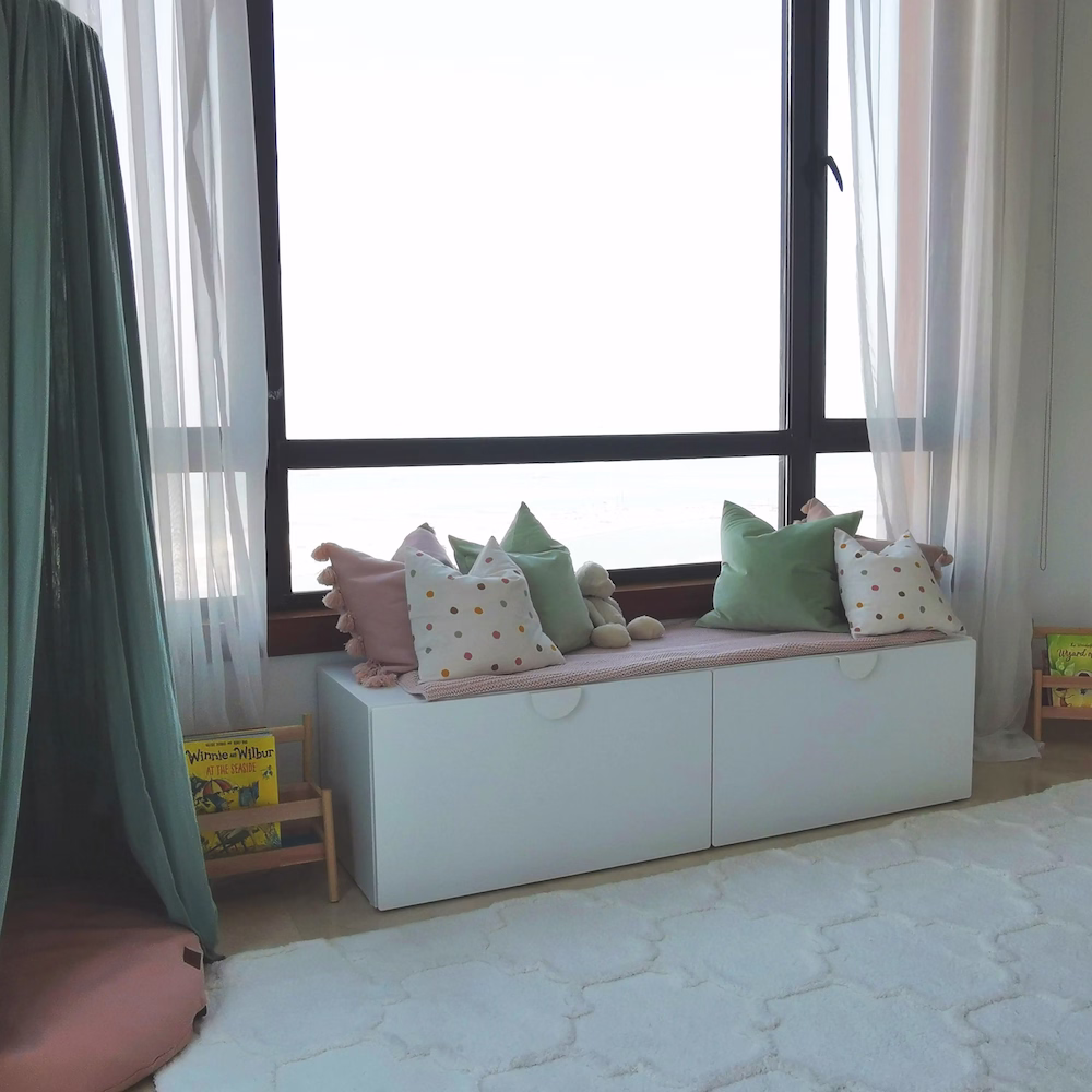 Mint green canopy reading nook in girls’ bedroom with cushions and books creating a comfortable, imaginative corner for a child.