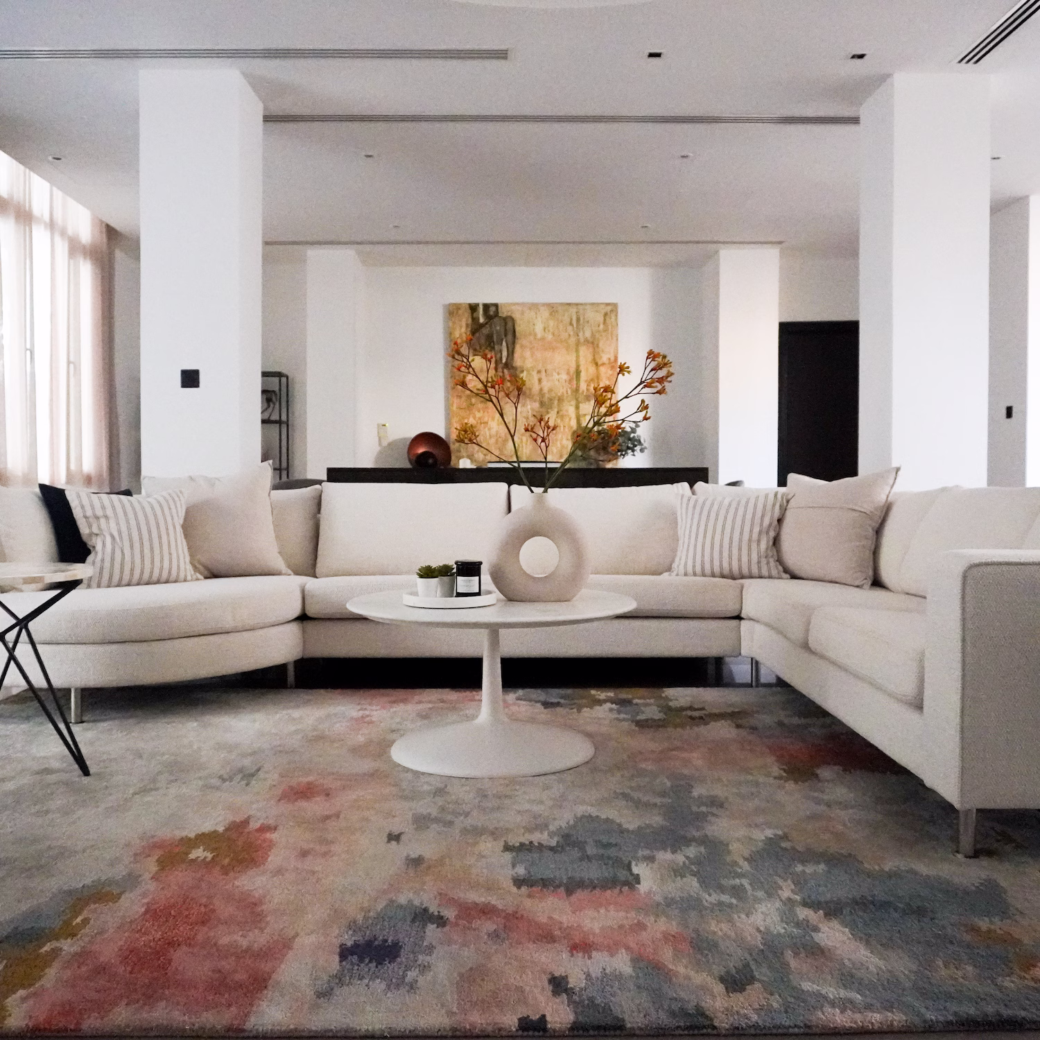 Warm living room interior design in Doha by Roberts Renovations featuring layered West Elm rugs, curated accessories, and colourful artwork.
