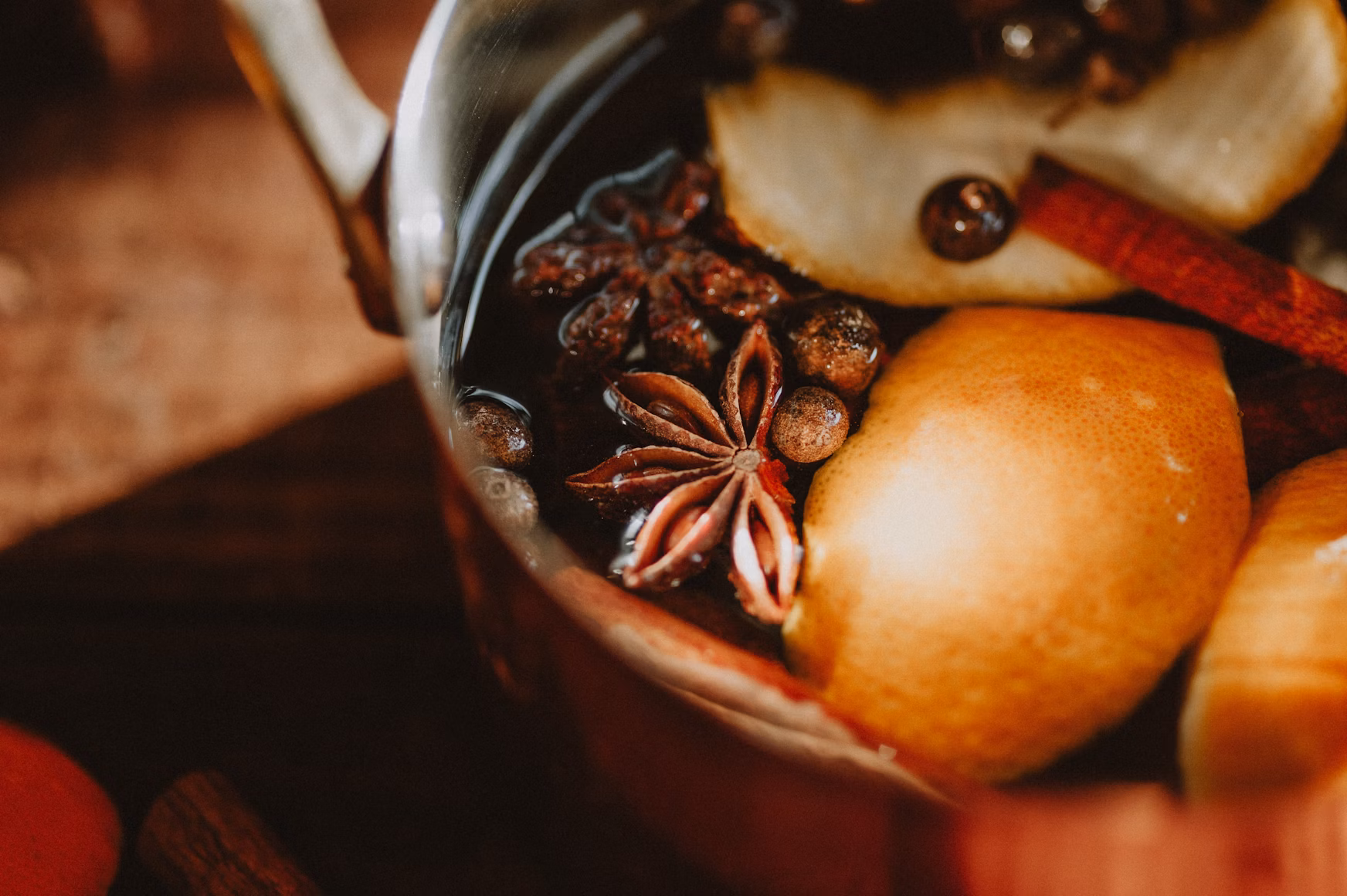Close-up of cinnamon sticks, nutmeg and star anise beside a warm drink, capturing the comforting scents of winter home décor.