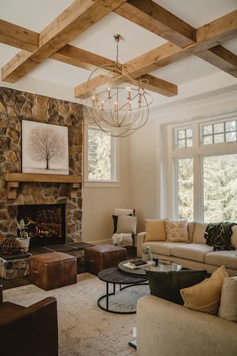 Elegant living room with stone fireplace, neutral décor and warm lighting, styled to reflect cosy winter interior design ideas for 2025.