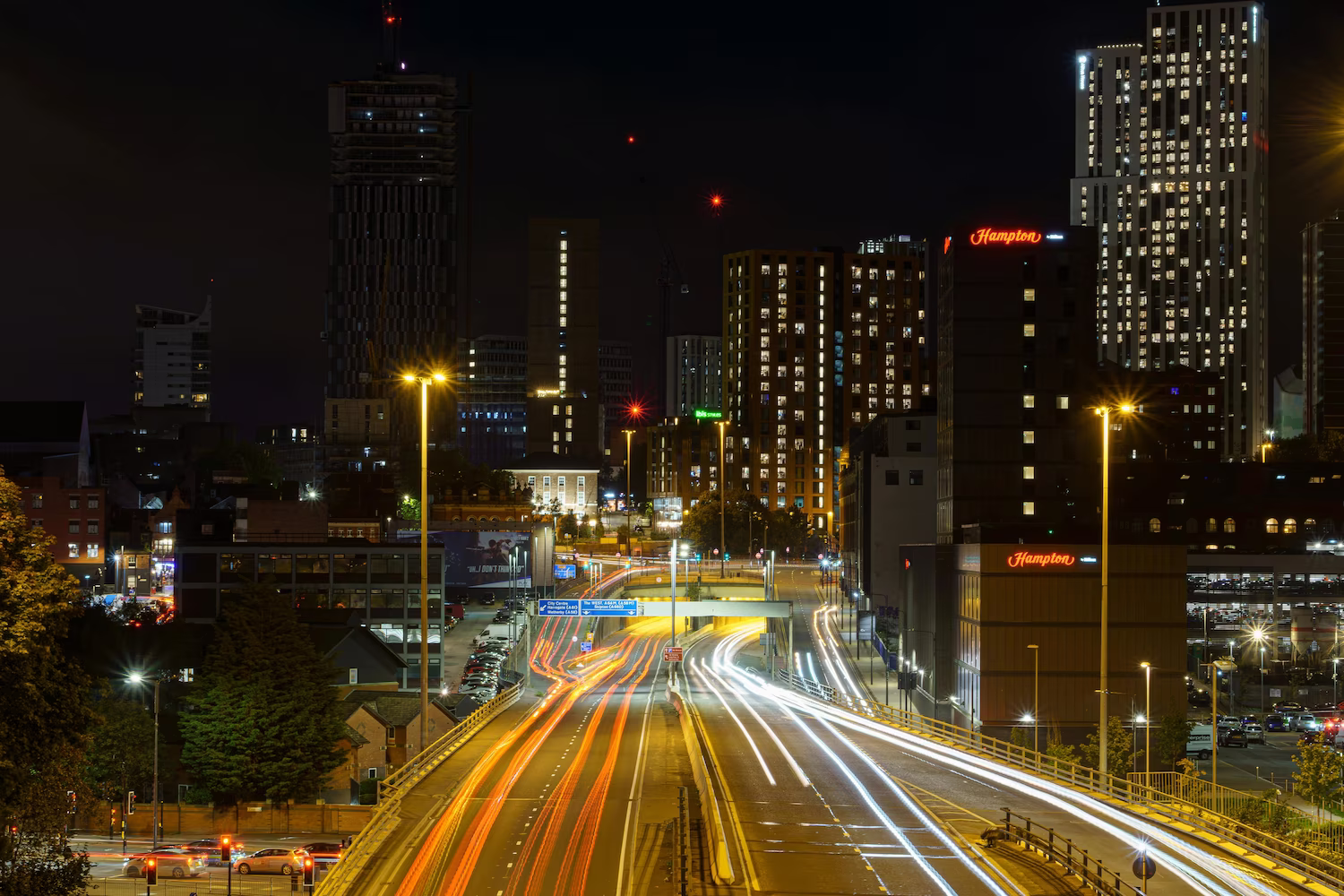 Leeds city centre skyline at night with light trails on the motorway, representing property investment and financial growth in the UK.