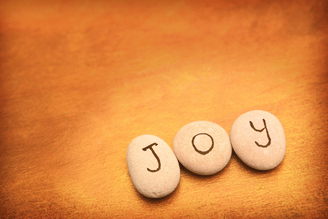 A poster with a  oft brown background and three stones spelling the word joy to remind us that joy is always with us