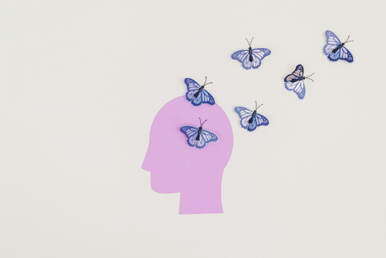 A purple silhouette of a head with several blue butterflies flying around and on top of it, against a light background.