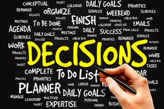 A hand writes on a chalkboard-style word cloud with bold “DECISIONS,” “DAILY GOALS,” and “DAILY GOALS TO DO LIST,” surrounded by planning and productivity keywords like “priorities,” “planner,” and “expertise.”