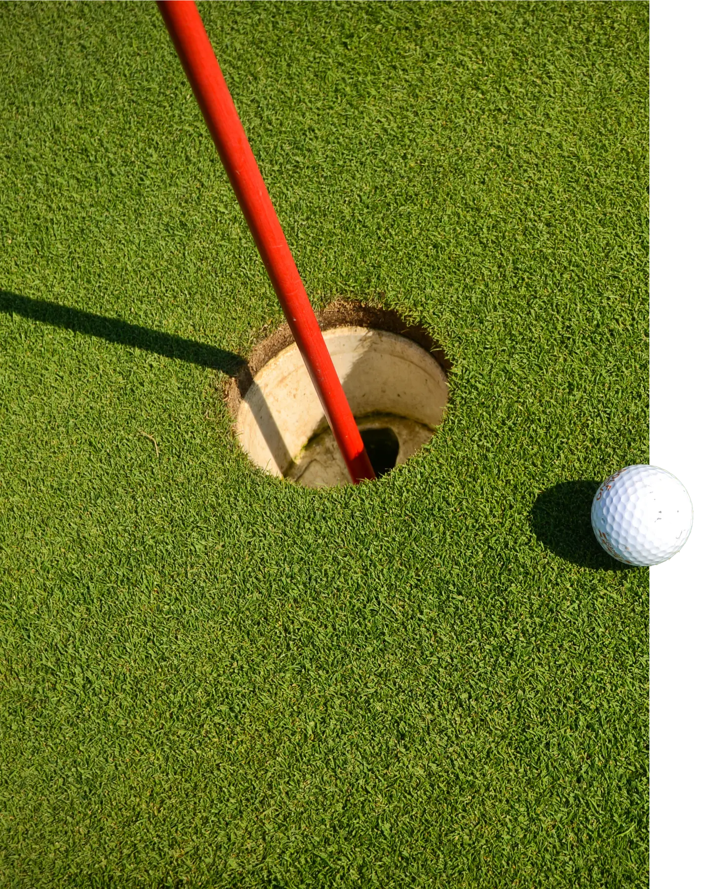 Golf course ball rolling into the hole with red flag pole.