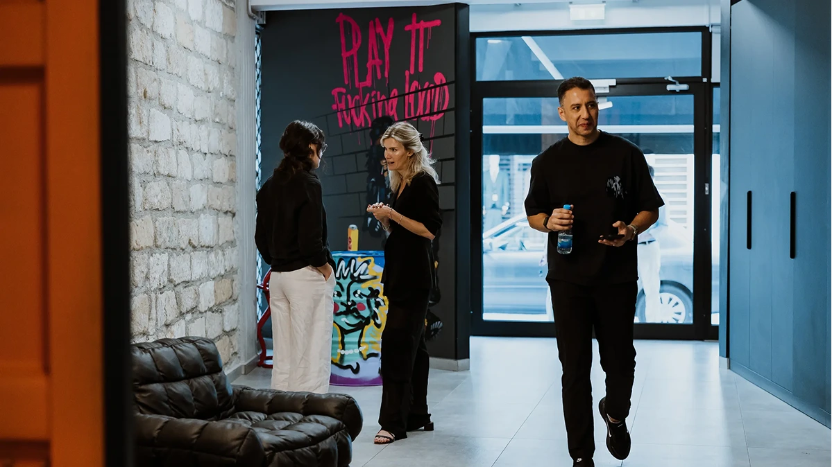 People talking in a modern hallway with graffiti artwork and large windows