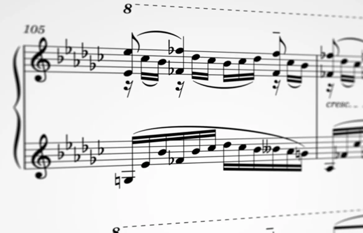 Close-up of sheet music showing treble clefs, multiple flat accidentals, and a series of musical notes with slurs and staccato markings.