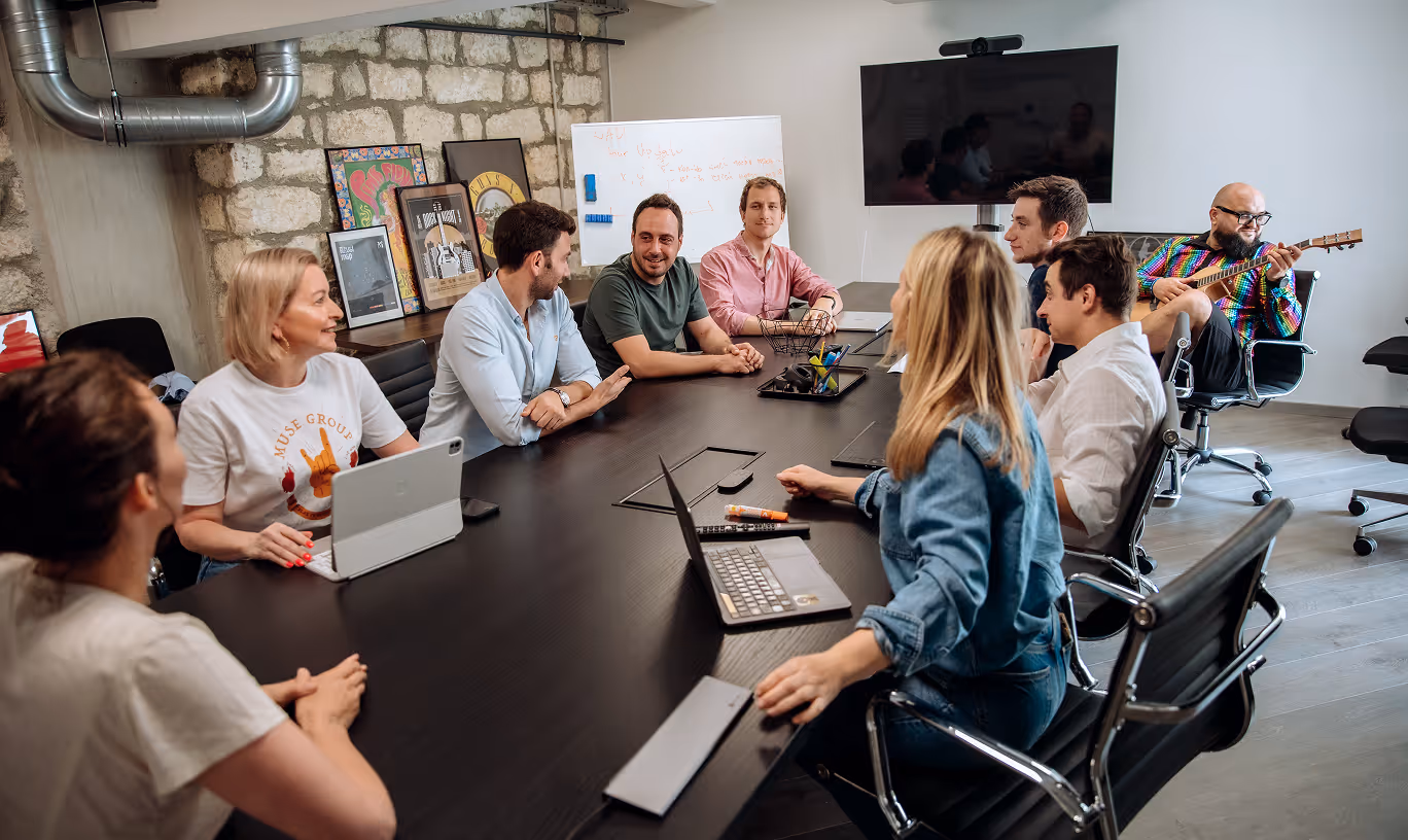 Muse Group team collaborating in a meeting with laptops and musical instruments
